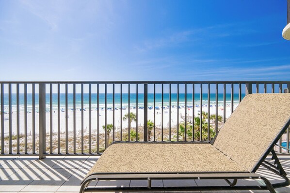 A balcony with a view of a beach and ocean.