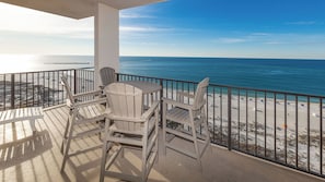 Ein Balkon mit Blick auf den Strand und den Ozean, inklusive Tisch und Stühlen.