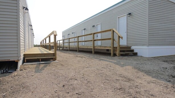 A row of single-story buildings with a wooden ramp leading to a door. - Golden Prairie Lodge (Kerrobert)
