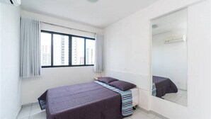 Habitació petita i senzilla amb un llit, una finestra, un mirall i un radiador.