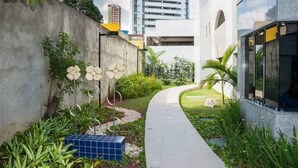 Un camí que condueix a un edifici de disseny modern, envoltat de vegetació i una petita zona de jardí.