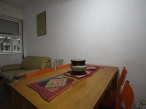 A dining area with a wooden table, a patterned table runner, and a decorative bowl.