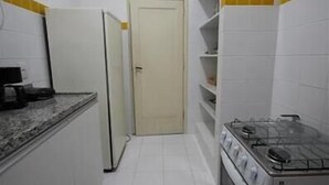 Una cocina estrecha con gabinetes blancos, un horno y un refrigerador.