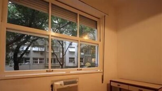 Una habitación con un ventanal grande, un radiador y un escritorio.