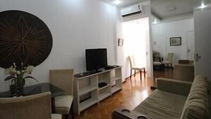 A living room with a sofa, a TV, a coffee table, and a decorative wall piece. - GoHouse Leopoldo 602 (Rio de Janeiro)