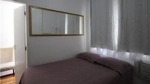 A bedroom with a bed, a mirror, and a window with curtains. - GoHouse Leopoldo 602 (Rio de Janeiro)