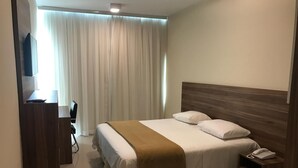 Una habitación de hotel con una cama, un escritorio, una silla, un teléfono y un televisor.