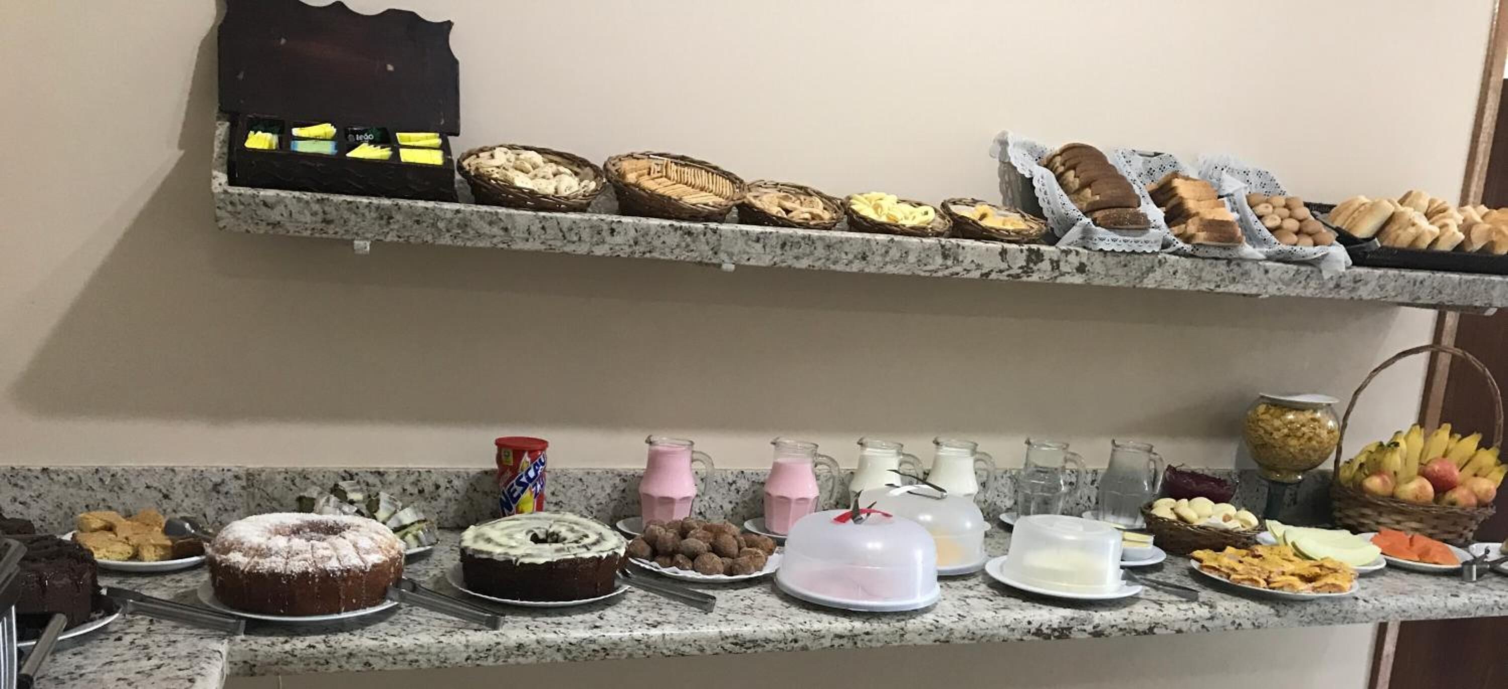 A buffet with various desserts and beverages on a granite countertop.