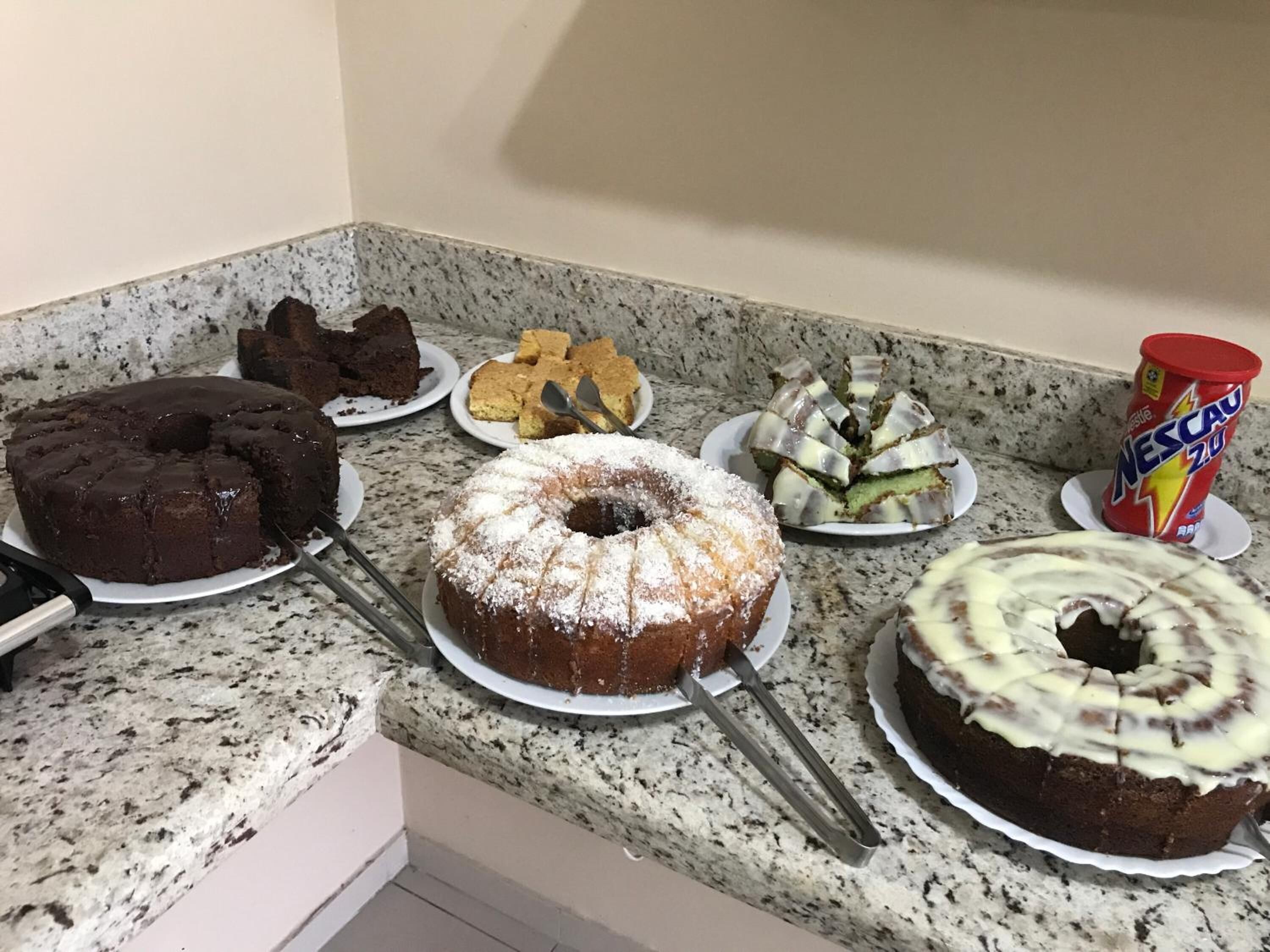 Uma bancada de cozinha com vários bolos e uma lata de Nescafé Zest.
