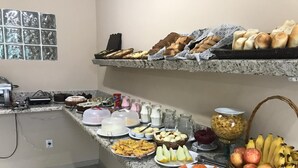 Un bufé con diversos alimentos, entre ellos frutas, pasteles y productos lácteos.