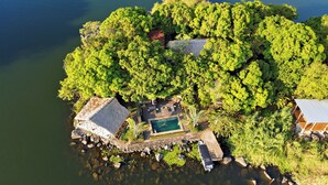 An aerial view of a secluded island with a swimming pool, a thatched-roof structure, and a small dock. - Isleta El Espino Ecolodge (Granada)