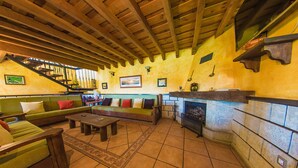 A cozy living room with a fireplace, green sofas, wooden beams, and a staircase. - Hotel Rural La Noria (Ciudad Rodrigo)