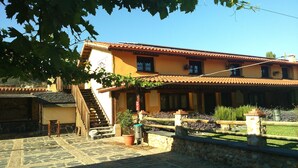 A traditional building with a tiled roof, a stone staircase, and a courtyard with plants and a stone wall. - Hotel Rural La Noria (Ciudad Rodrigo)