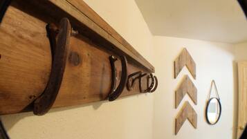 A wooden coat rack with several horseshoes and a mirror on the wall.