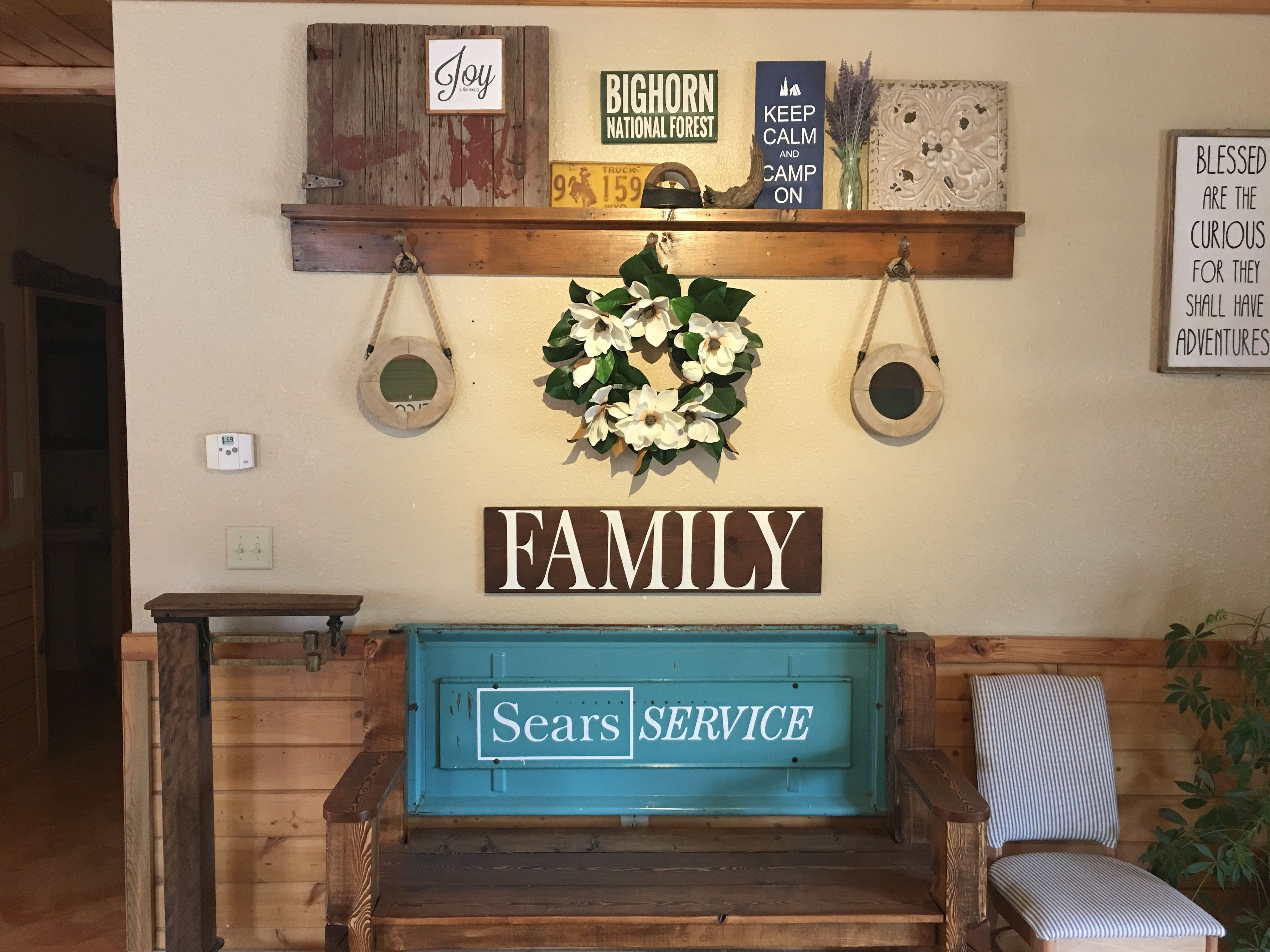 Un banc en bois orné d’une enseigne « Service Sears », d’une enseigne « Famille » et de divers objets décoratifs, notamment une enseigne « Joie », une enseigne « Forêt nationale de Big Horn » et une enseigne « Gardez votre calme et continuez à camper ».