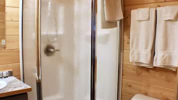 Un baño con paneles de madera, una ducha con cerramiento de vidrio, un inodoro y un lavabo.