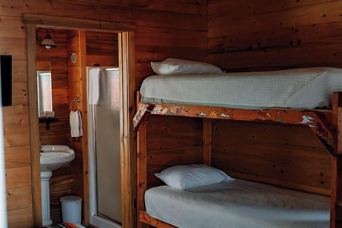 A wooden cabin with bunk beds, a sink, and a ceiling fan.