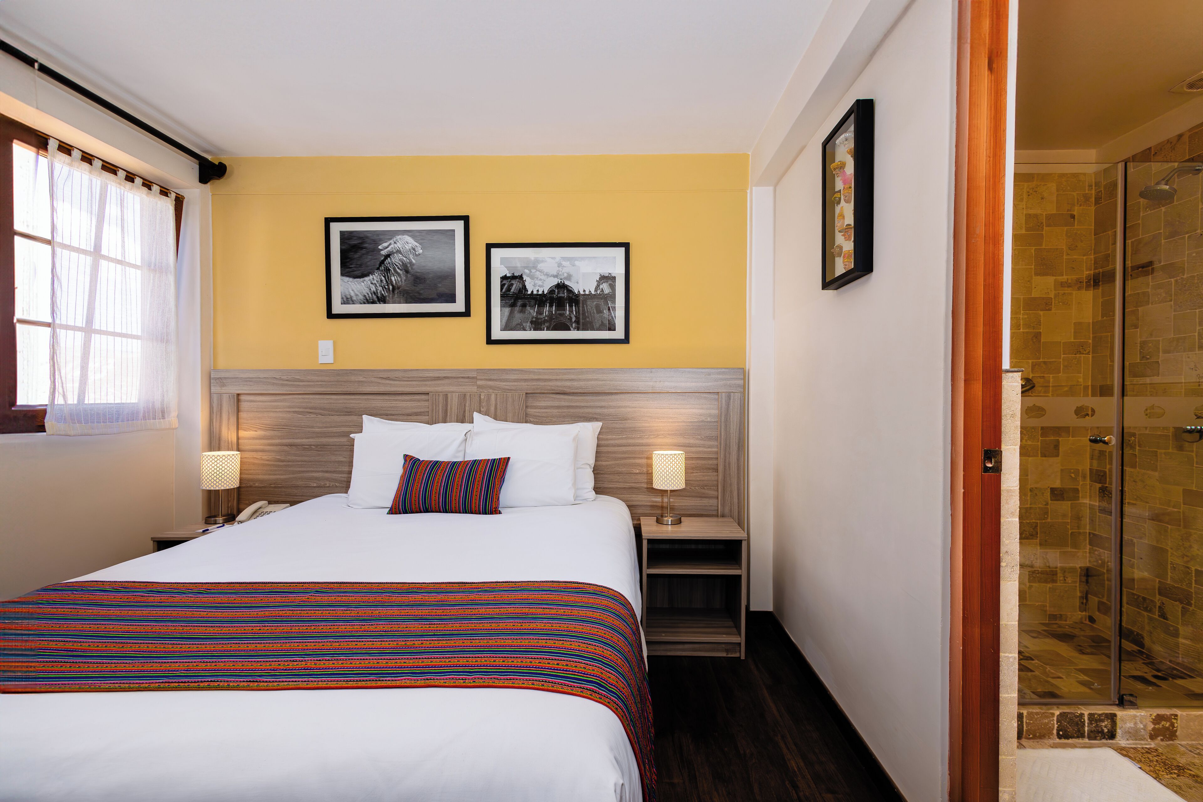A hotel room with a large bed, a bedside table with a lamp, and a framed picture on the wall.