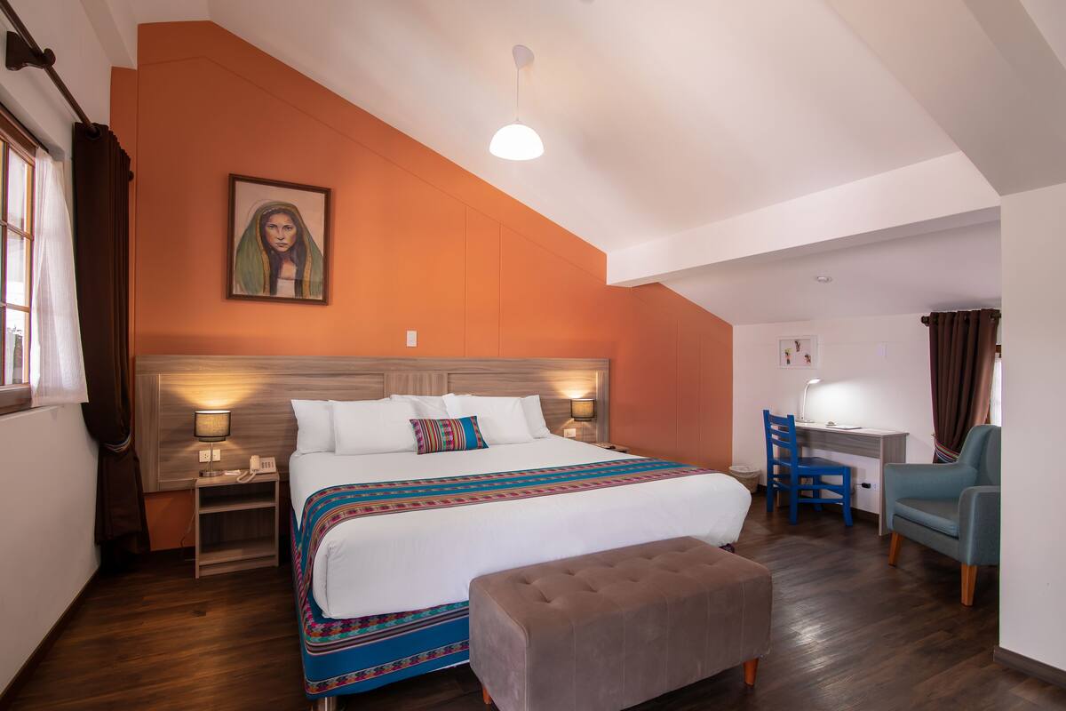 Une chambre d’hôtel avec un grand lit, un bureau, une chaise et une petite table.
