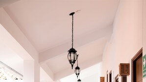 Un pasillo de hotel con una escalera que lleva a una habitación, un comedor con sillas y una mesa, y un espejo decorativo.