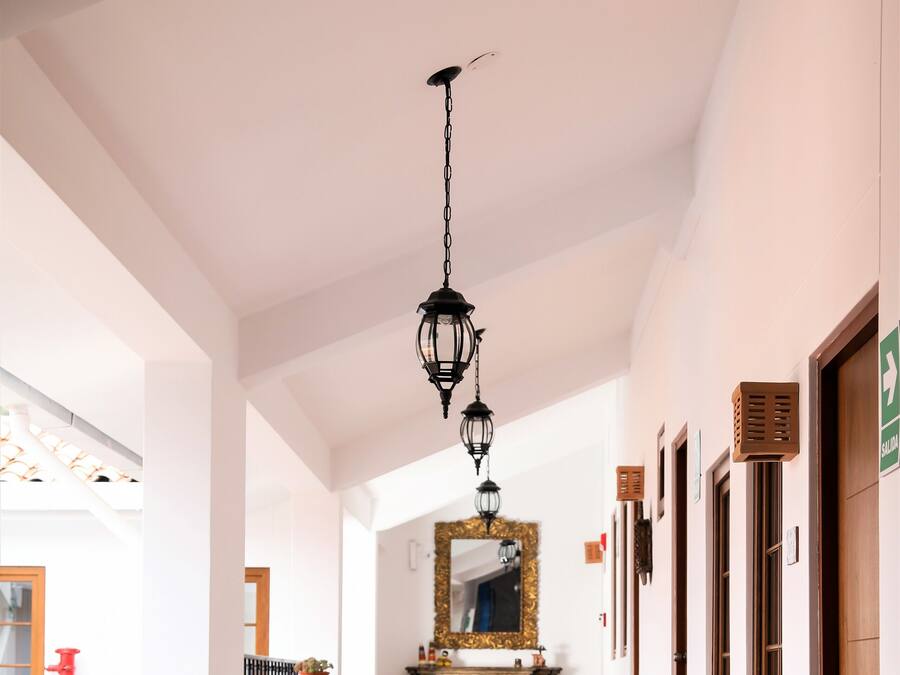 A hotel corridor with a staircase leading to a room, a dining area with chairs and a table, and a decorative mirror.
