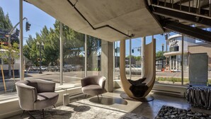A modern interior with large windows, a concrete ceiling, and a view of the street outside. - Jupiter NEXT (Portland)