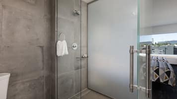 A modern bathroom with a glass shower enclosure, a toilet, and a towel rack.