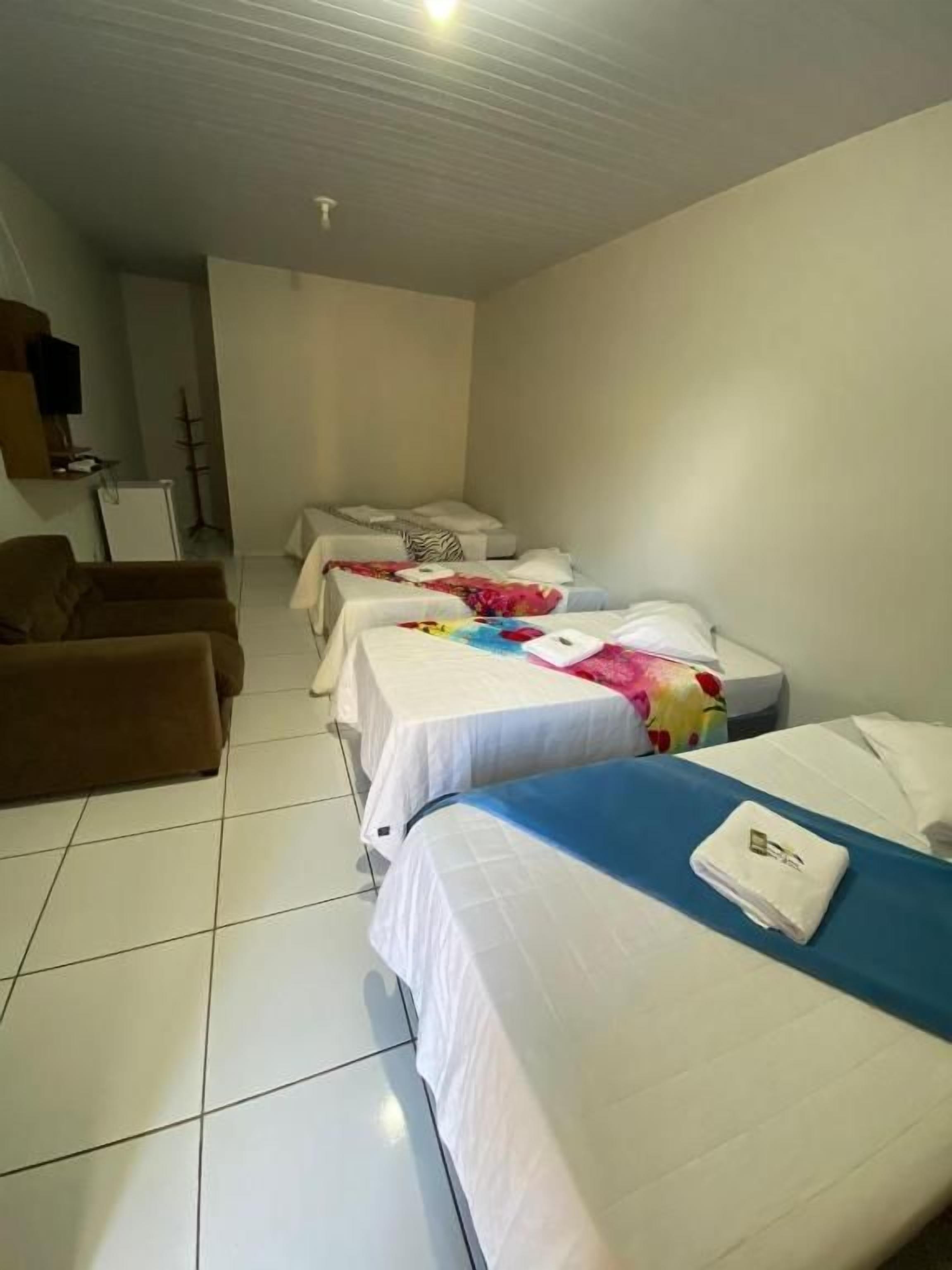 A hotel room with two single beds, a sofa, a desk, and a television.