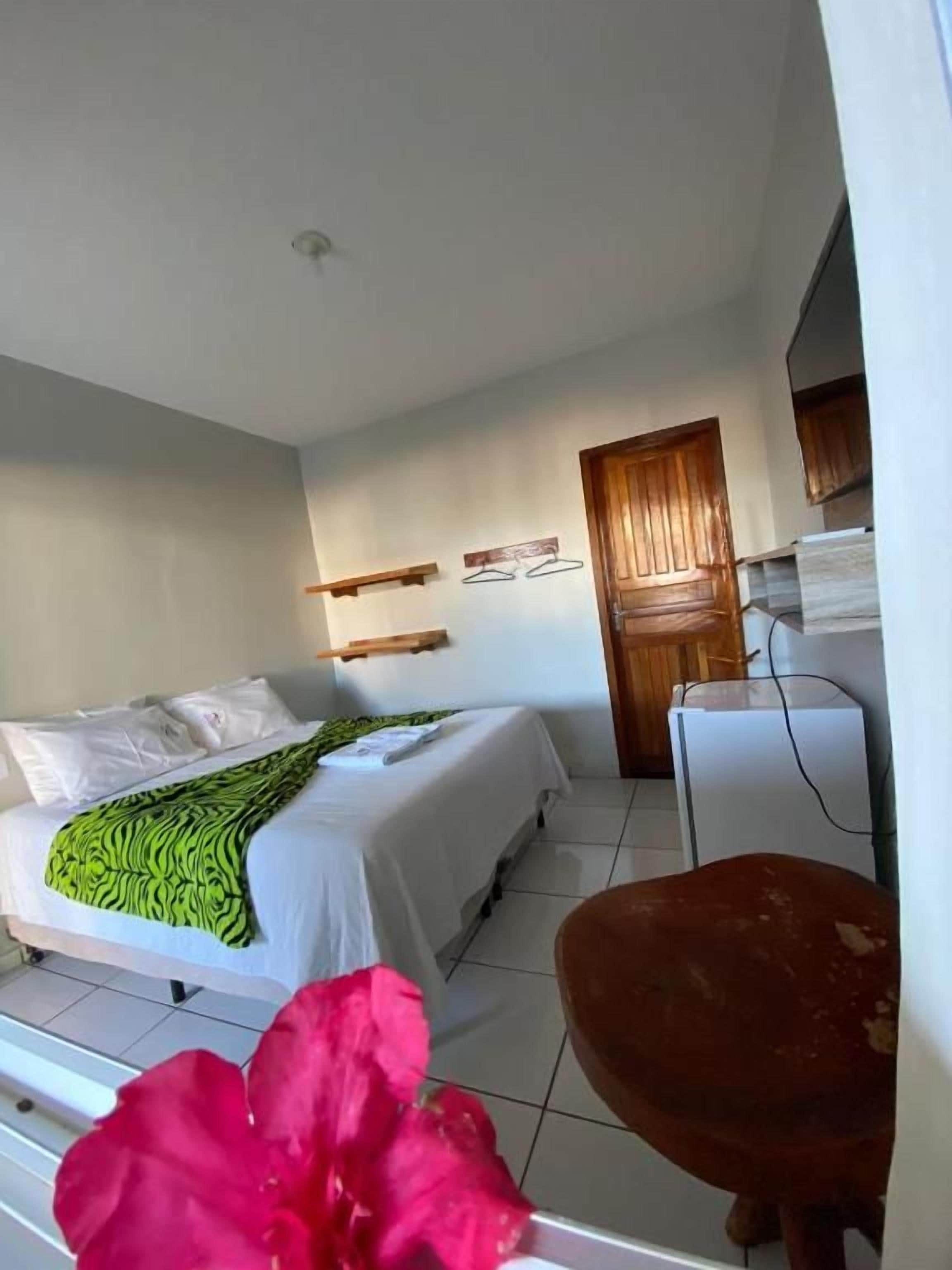 A bedroom with a bed, a desk, and a chair. There is a door and a window.