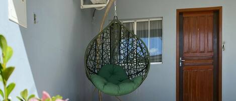 Ein Zimmer mit Hängesessel, Tür und Fenster.