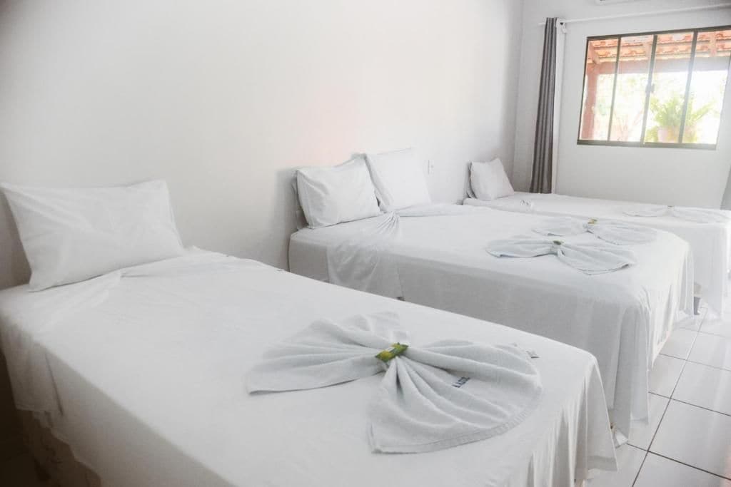 Una habitación de hotel con dos camas individuales, cada una con una toalla doblada con cuidado.