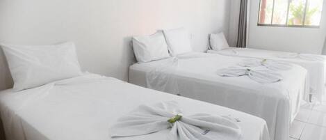 Una habitación de hotel con dos camas individuales, cada una con una toalla doblada con cuidado.