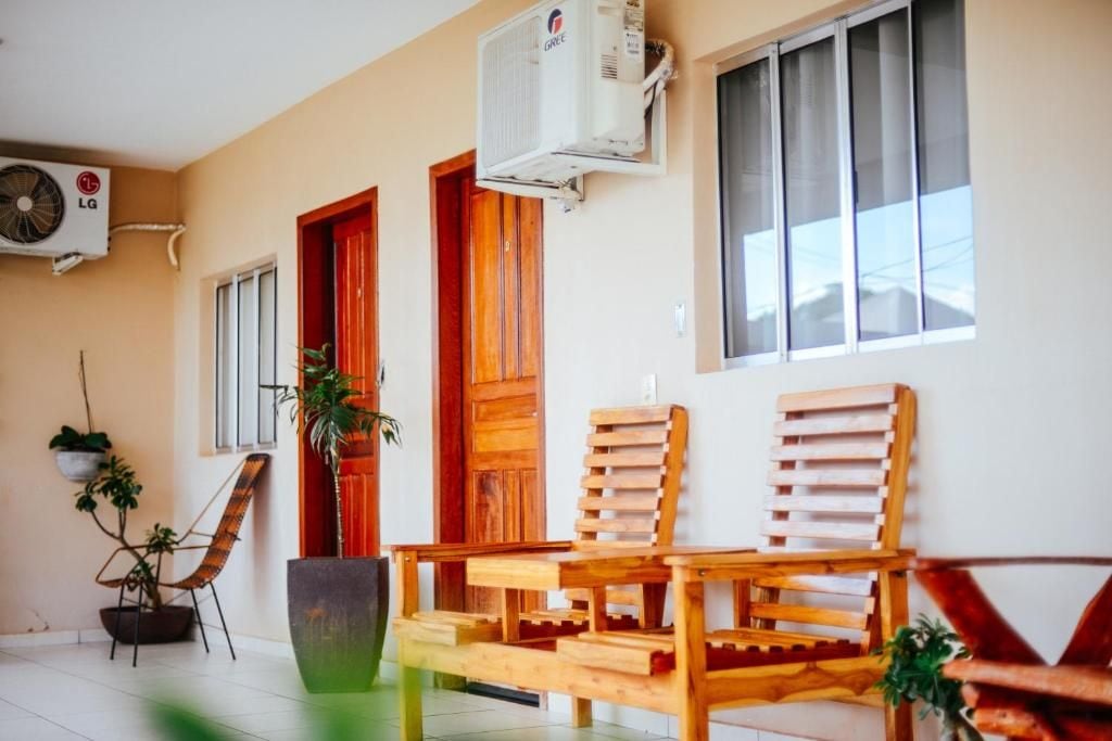 A room with a wooden bench, a potted plant, and an air conditioning unit mounted on the wall.
