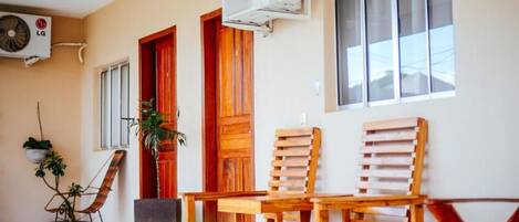 A room with a wooden bench, a potted plant, and an air conditioning unit mounted on the wall.