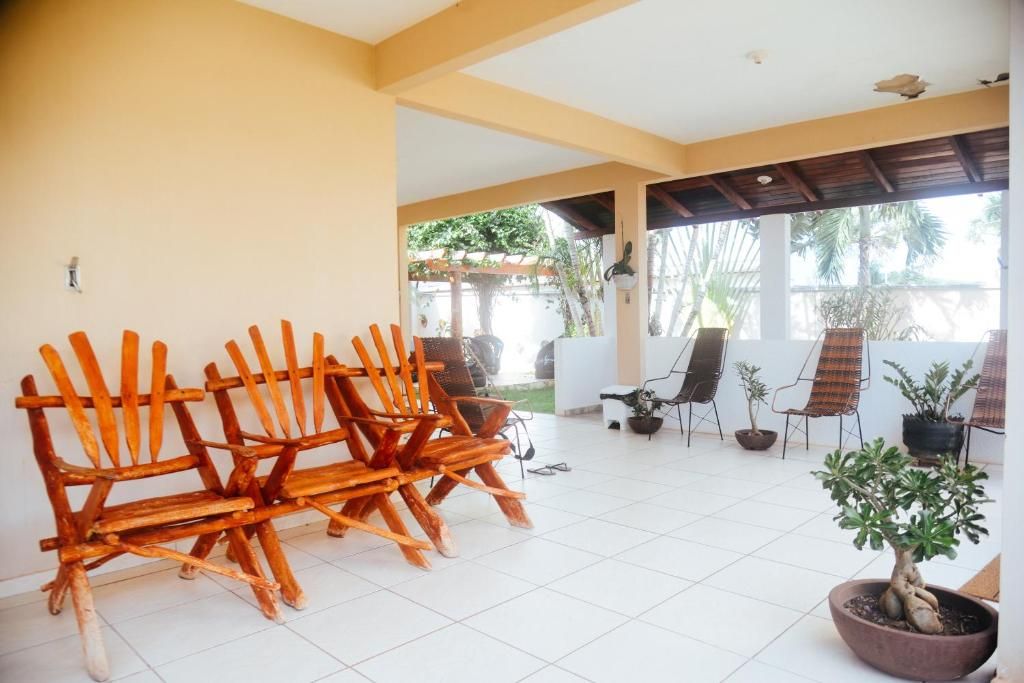 Un área de patio techada con sillas de madera y plantas en macetas.
