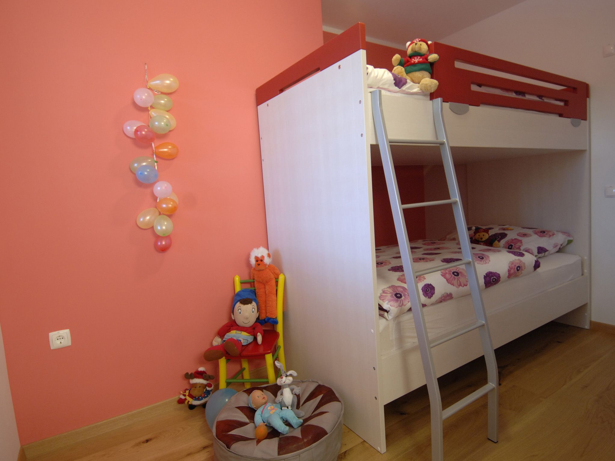A bunk bed room with a ladder, a toy car, and a toy train.