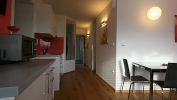 Eine moderne Küche mit Mikrowelle, einem roten Gerät und einem Essbereich mit Tisch und Stühlen.