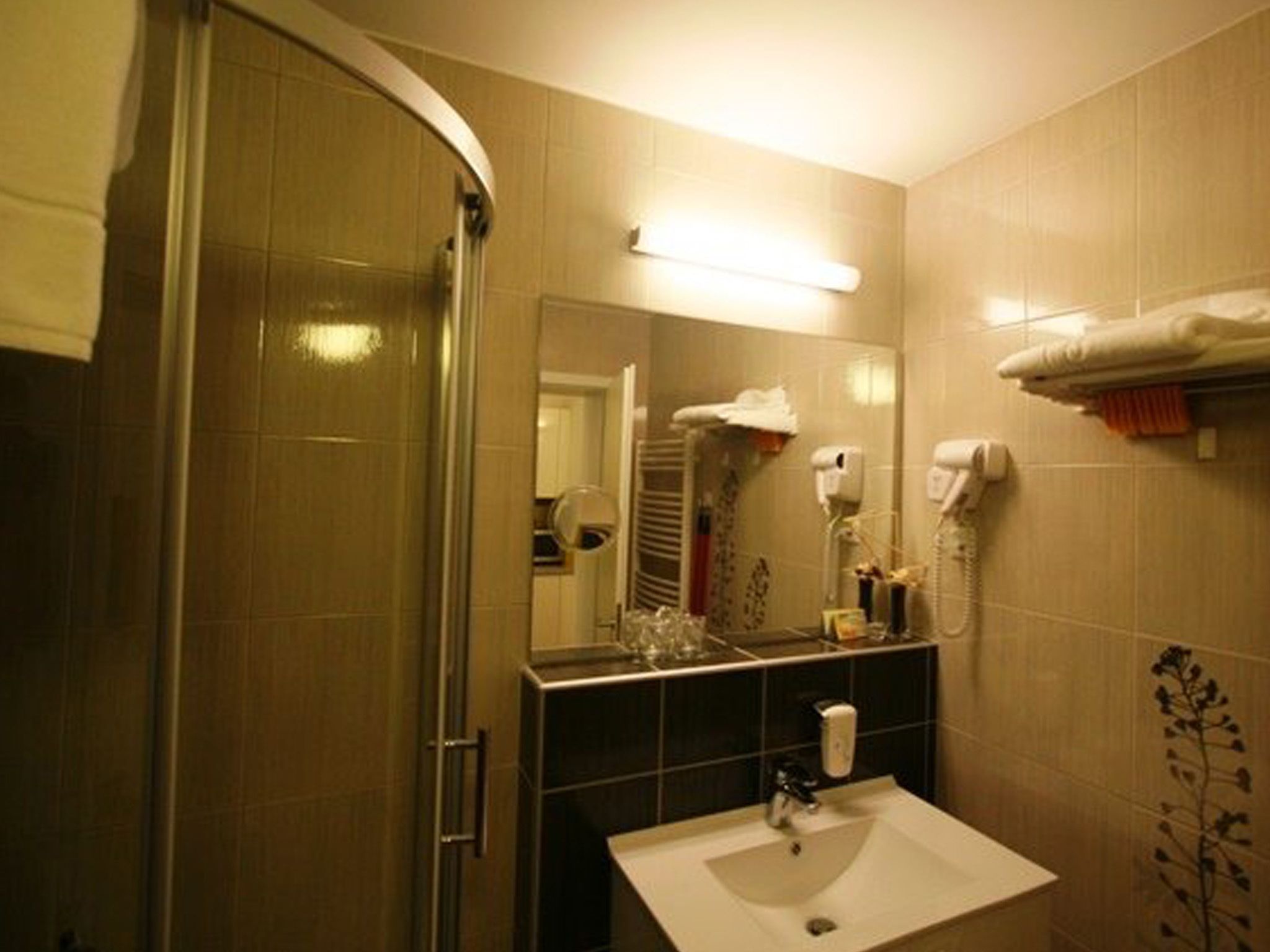 A bathroom with a glass shower enclosure, a sink with a mirror above it, and a towel rack with towels.