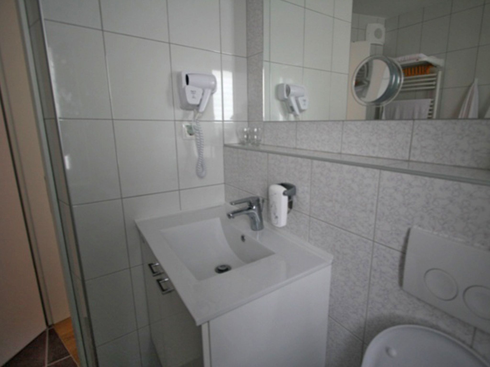 Une salle de bain avec un lavabo blanc, un miroir et des toilettes.