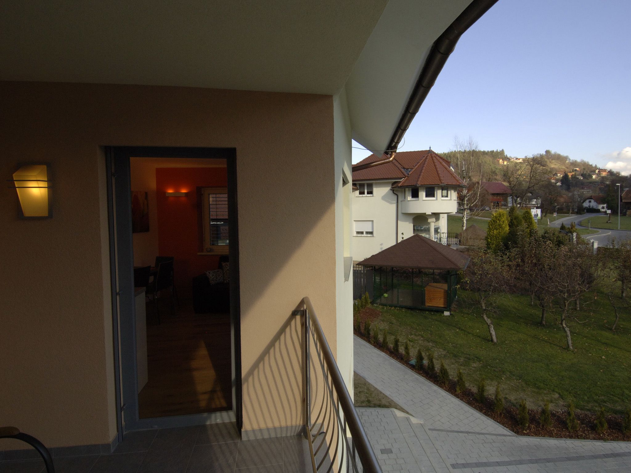 Un balcón con vista a una zona residencial, que incluye casas y una calle.