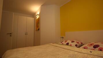 Een slaapkamer met een bed, een kledingkast en een geel accentmuur.