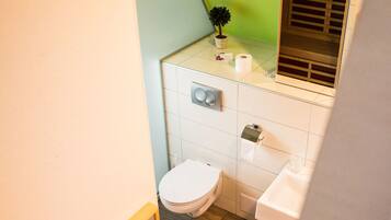 A small bathroom with a toilet, sink, and a potted plant on the counter.