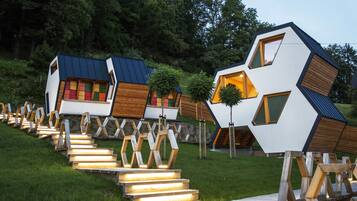 A series of modern, geometrically shaped cabins with wooden accents and glass windows, connected by wooden walkways.