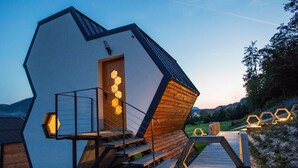 Un edificio moderno de forma hexagonal con fachada de madera y una escalera que lleva a una terraza.