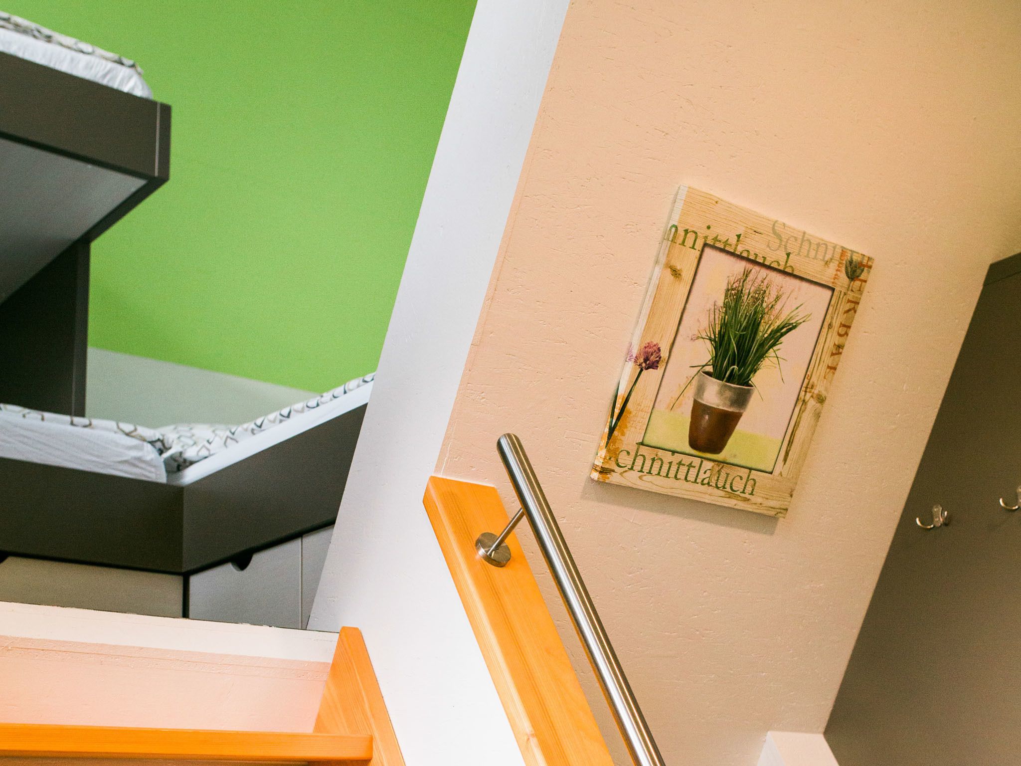 A room with a green wall, a wooden door, and a framed picture of a plant on the wall.