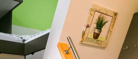 A room with a green wall, a wooden door, and a framed picture of a plant on the wall.