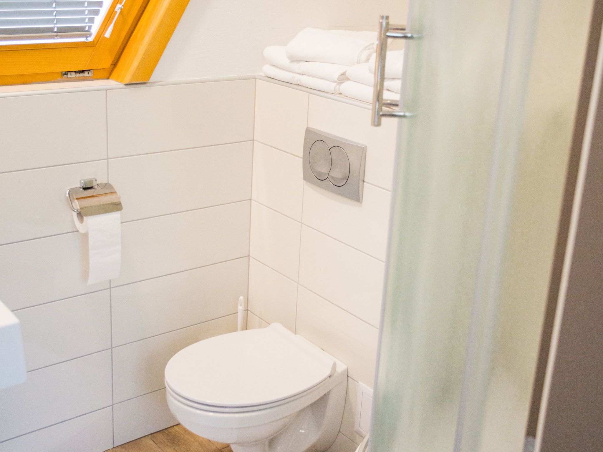 Un baño pequeño y limpio con inodoro, toallero y dispensador de papel higiénico.