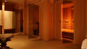 Pasillo de hotel con puertas de madera y una pequeña mesa con sillas.