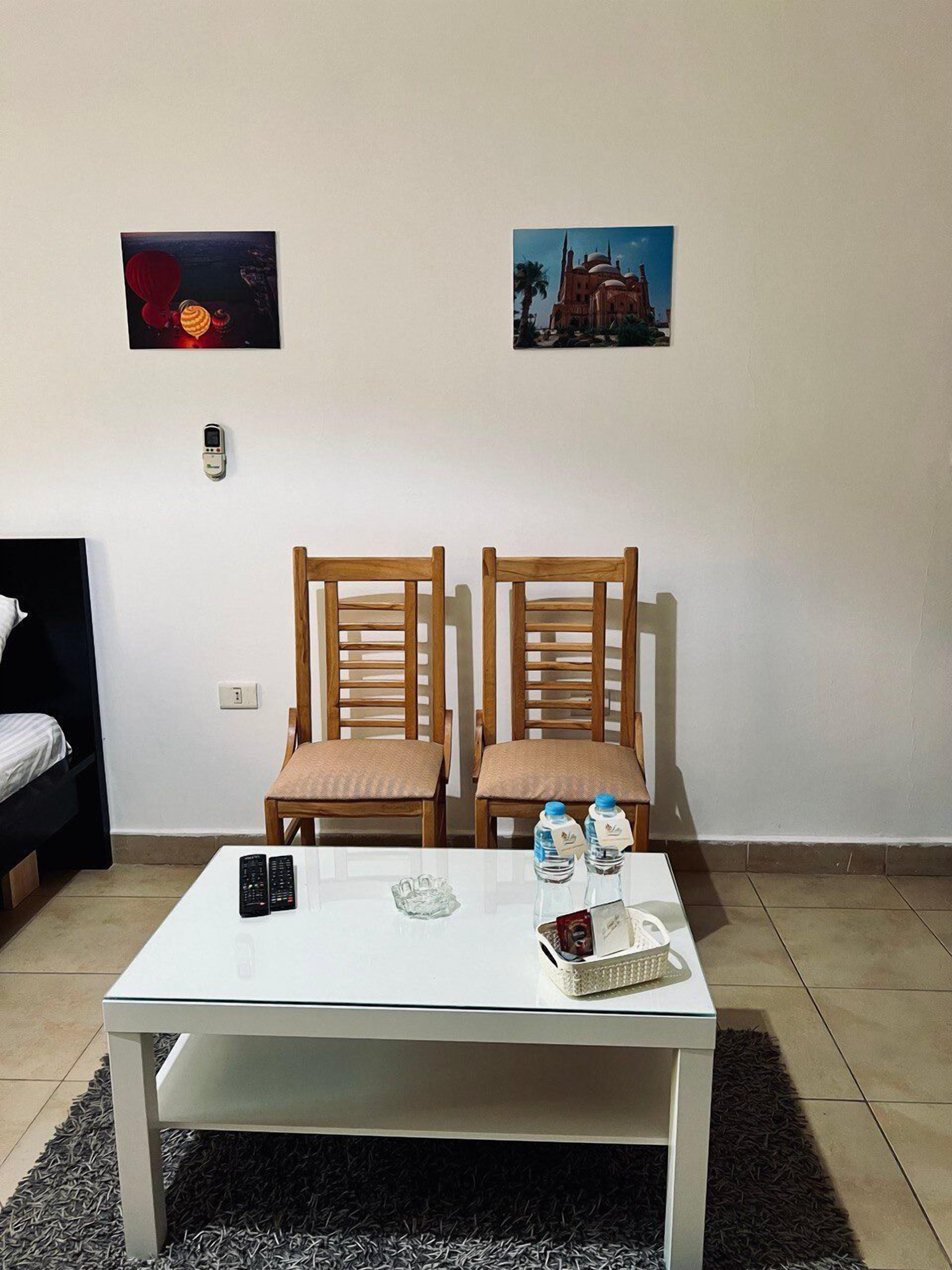 A room with two wooden chairs, a white table, and two paintings on the wall.