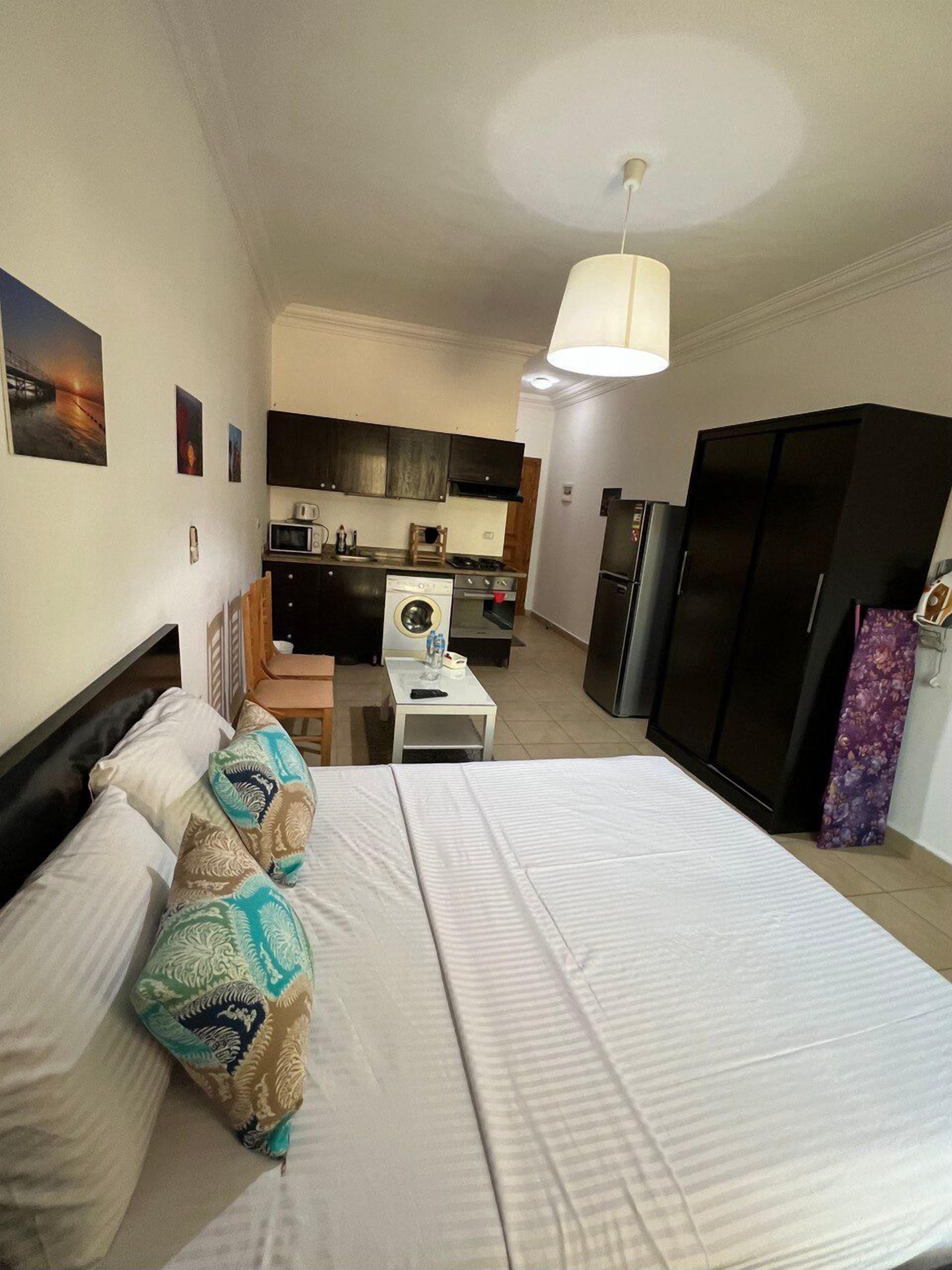 Una camera d'albergo compatta con un letto, un angolo cottura, un frigorifero e un tavolo da pranzo.